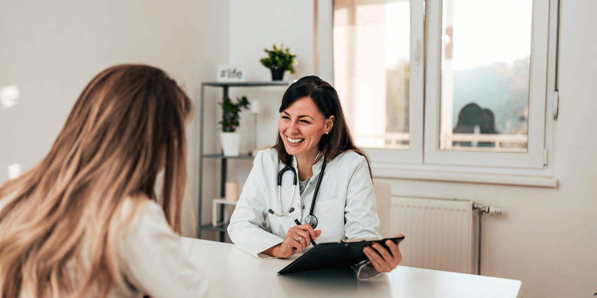 Doctor holding a clip board and smiling at patient